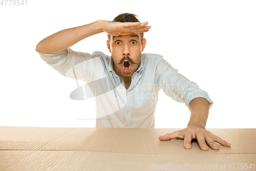 Image of Young man opening the biggest postal package isolated on white