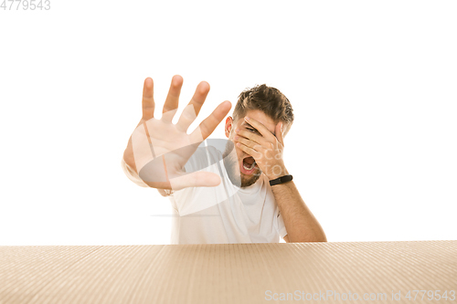 Image of Young man opening the biggest postal package isolated on white