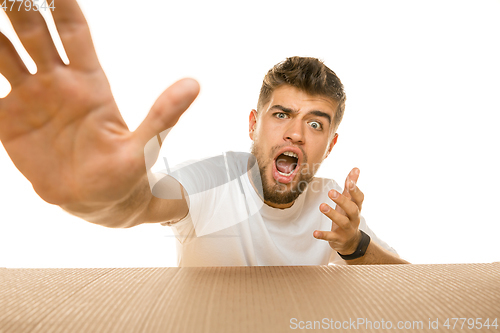 Image of Young man opening the biggest postal package isolated on white