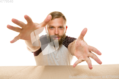 Image of Young man opening the biggest postal package isolated on white