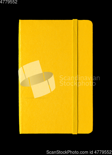 Image of Yellow closed notebook isolated on black