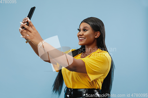 Image of African-american young woman\'s half-length portrait on blue background