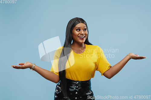 Image of African-american young woman\'s half-length portrait on blue background