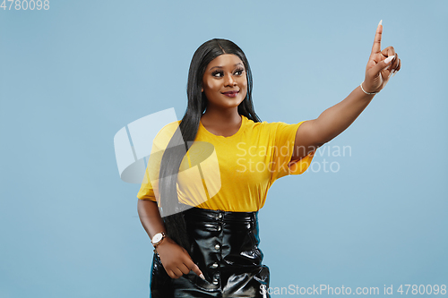 Image of African-american young woman\'s half-length portrait on blue background