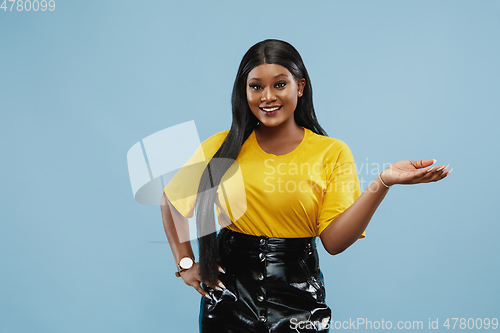 Image of African-american young woman\'s half-length portrait on blue background