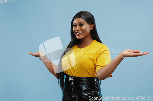Image of African-american young woman\'s half-length portrait on blue background