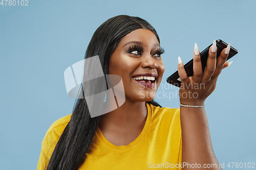 Image of African-american young woman\'s half-length portrait on blue background