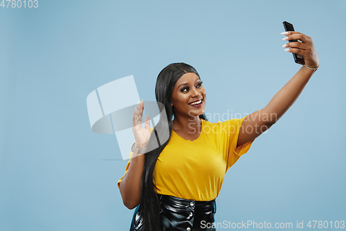 Image of African-american young woman\'s half-length portrait on blue background