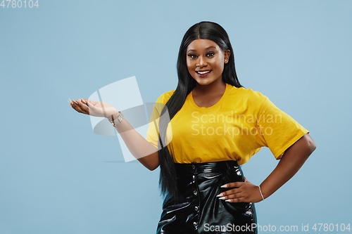 Image of African-american young woman\'s half-length portrait on blue background