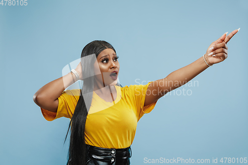 Image of African-american young woman\'s half-length portrait on blue background