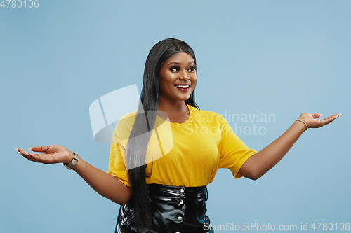 Image of African-american young woman\'s half-length portrait on blue background