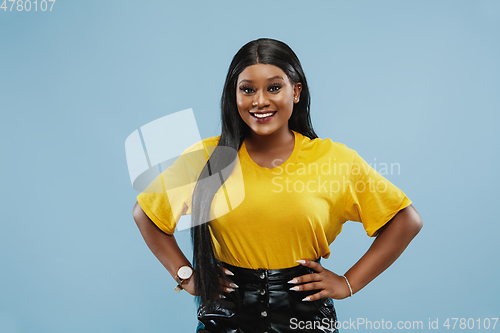 Image of African-american young woman\'s half-length portrait on blue background