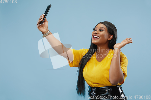 Image of African-american young woman\'s half-length portrait on blue background