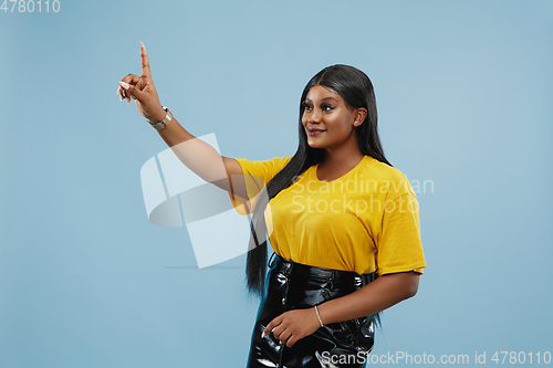 Image of African-american young woman\'s half-length portrait on blue background