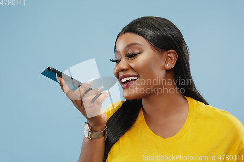 Image of African-american young woman\'s half-length portrait on blue background