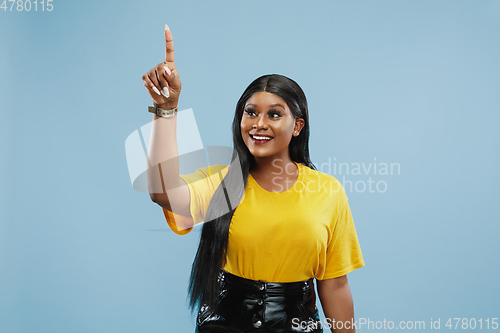 Image of African-american young woman\'s half-length portrait on blue background