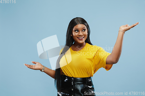 Image of African-american young woman\'s half-length portrait on blue background