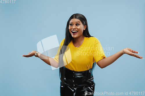 Image of African-american young woman\'s half-length portrait on blue background