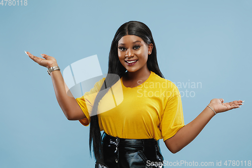 Image of African-american young woman\'s half-length portrait on blue background