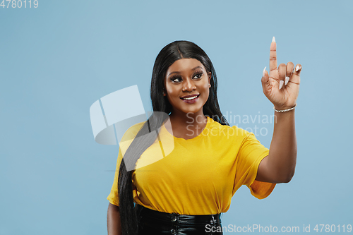 Image of African-american young woman\'s half-length portrait on blue background