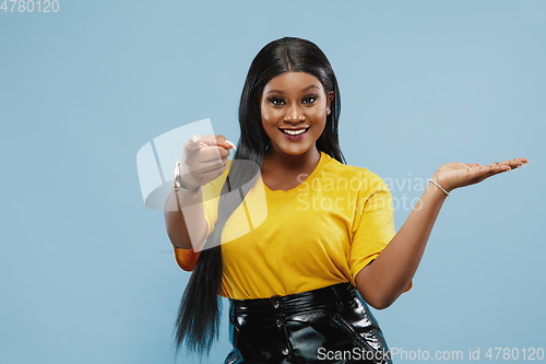 Image of African-american young woman\'s half-length portrait on blue background