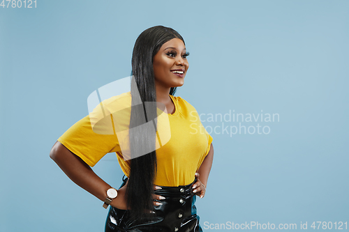 Image of African-american young woman\'s half-length portrait on blue background