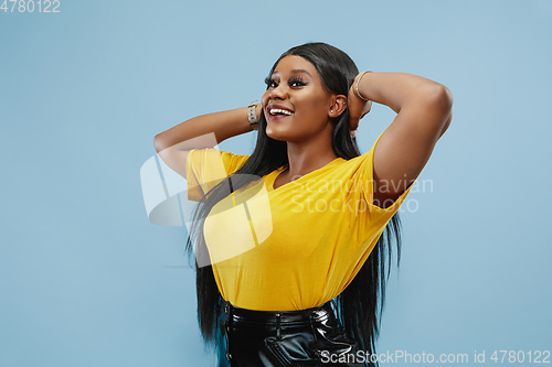 Image of African-american young woman\'s half-length portrait on blue background