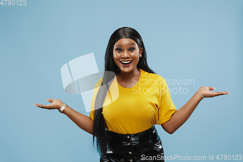 Image of African-american young woman\'s half-length portrait on blue background