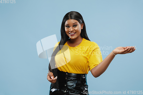 Image of African-american young woman\'s half-length portrait on blue background