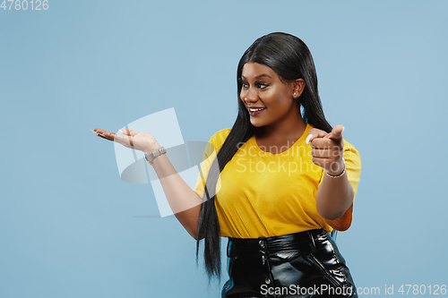 Image of African-american young woman\'s half-length portrait on blue background