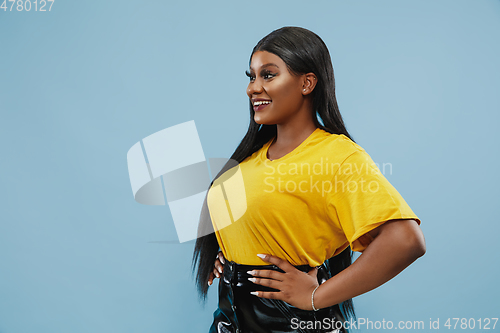 Image of African-american young woman\'s half-length portrait on blue background