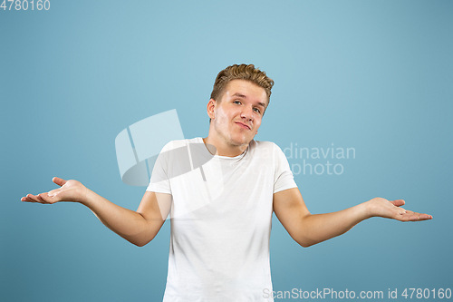 Image of Caucasian young man\'s half-length portrait on blue background