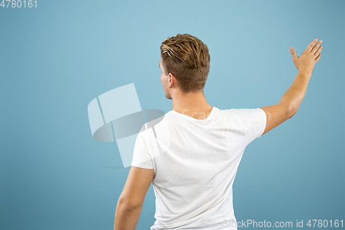 Image of Caucasian young man\'s half-length portrait on blue background