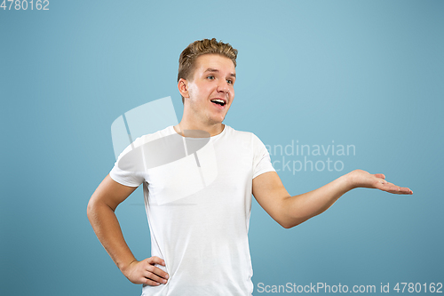 Image of Caucasian young man\'s half-length portrait on blue background
