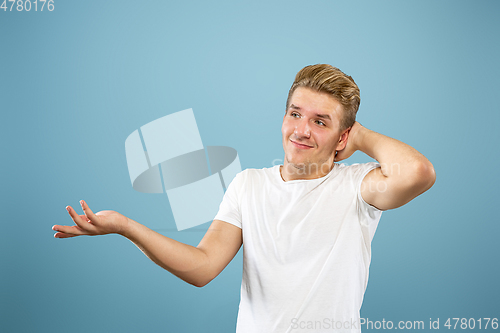 Image of Caucasian young man\'s half-length portrait on blue background