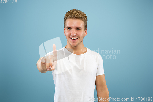 Image of Caucasian young man\'s half-length portrait on blue background