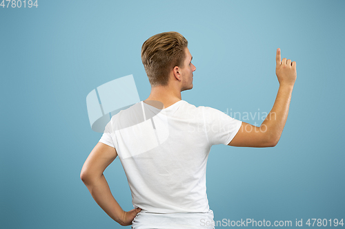 Image of Caucasian young man\'s half-length portrait on blue background