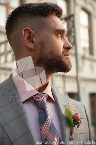 Image of Caucasian romantic young groom celebrating his marriage in city