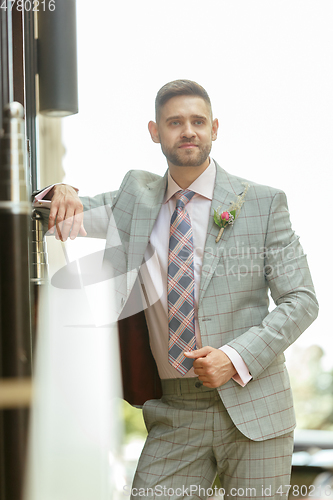 Image of Caucasian romantic young groom celebrating his marriage in city