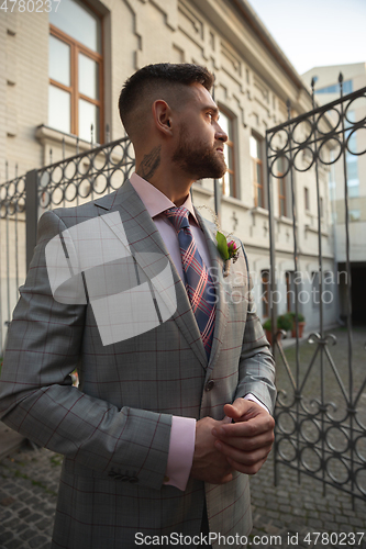 Image of Caucasian romantic young groom celebrating his marriage in city