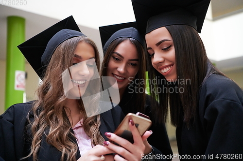 Image of students in mortar boards using smartphone