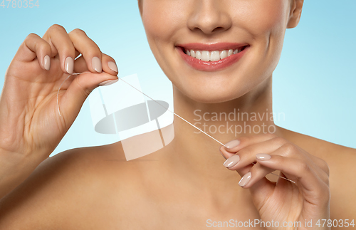 Image of smiling woman with dental floss cleaning teeth