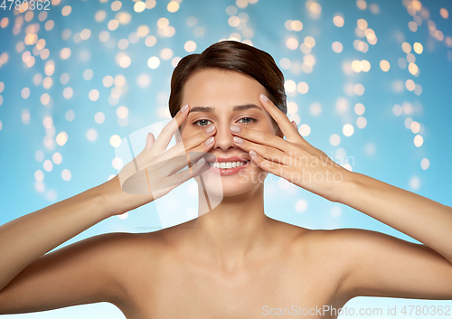 Image of beautiful young woman touching her face