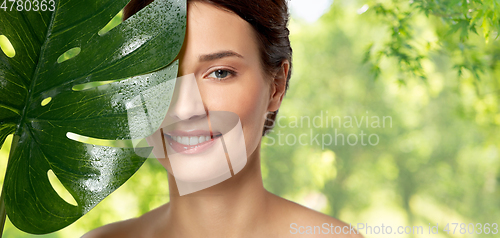 Image of beautiful young woman with green monstera leaf