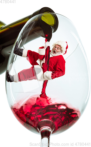 Image of Happy Christmas Santa Claus climbing on trickle of wine on white background