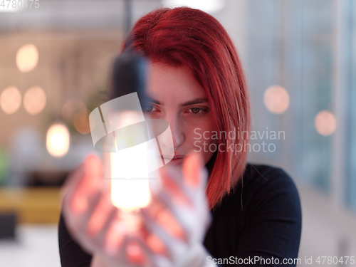 Image of businesswoman holding hand around light bulb