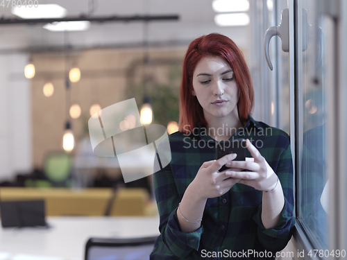 Image of redhead business woman at office using smart phone