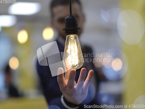 Image of businessman holding hand around light bulb