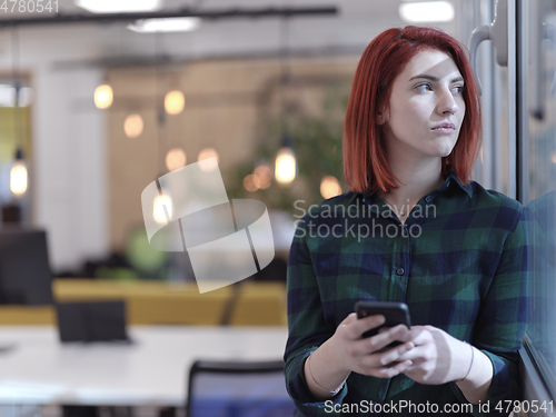 Image of redhead business woman at office using smart phone