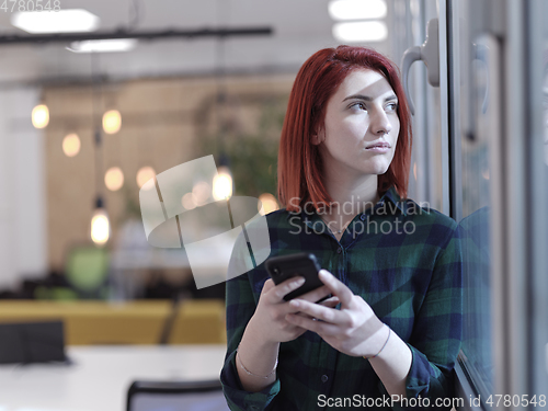 Image of redhead business woman at office using smart phone